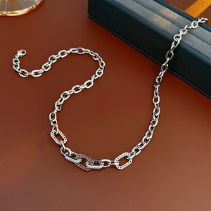 Detailed view of silver necklace featuring hollow square links set with cubic zirconia