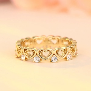 Macro shot of gold heart-shaped ring band with clear zircon accents and beaded details