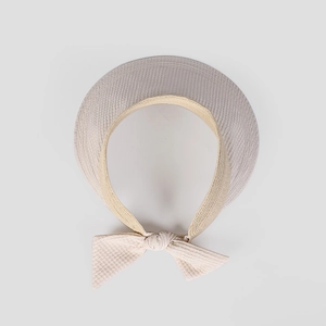 Vista dall'alto di un cappello a visiera estivo beige con un elegante fiocco in tessuto