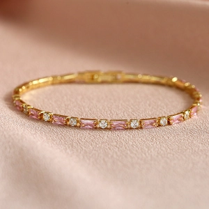 Macro detail of gold tennis bracelet with pink rectangular and white round zircons