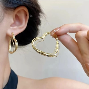 Detailed view of large gold heart hoop earrings with intricate twisted rope texture