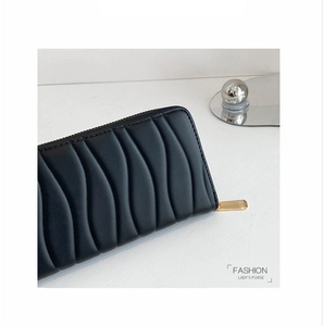 Detail view of wave pattern stitching on a black long leather purse with gold zipper