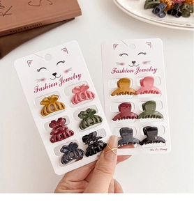 Close-up of 12 mini Morandi hair clips in various colors held in hand for size display