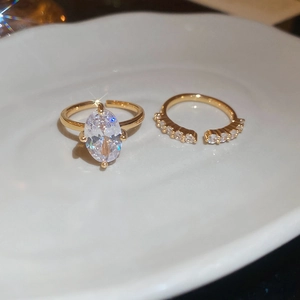 Close-up of gold oval zircon rings set with sparkling stones on white ceramic