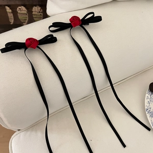 Detail of elegant black ribbon bow hair ties with handmade red roses and velvet texture