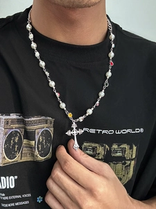 Detailed close-up of a silver cross pendant with faux pearls and colorful gemstones