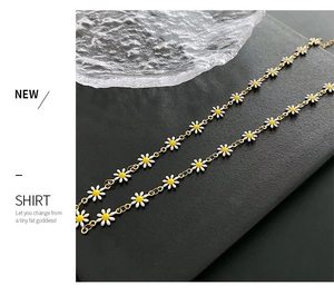 Close-up of daisy beaded necklace with gold chain on a black textured display
