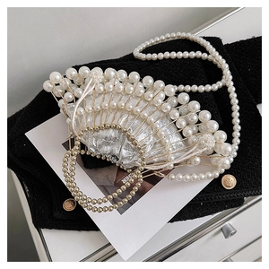 Close-up of pearl evening bag with gold handle and silver metallic lining on tweed