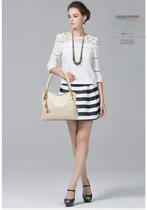 Detail of cream embossed handbag featuring gold handles and a metallic butterfly charm