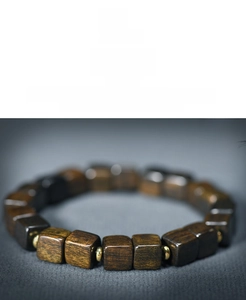Detailed view of square agarwood beads with golden spacers on a vintage wooden bracelet