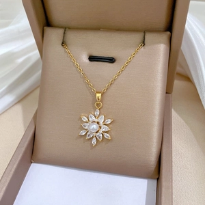 Close-up of pearl and zircon star flower pendant on a gold chain in a jewelry box