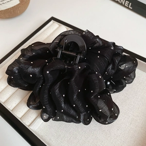Close-up of black organza bow hair claw with shimmering silver rhinestones and pearls
