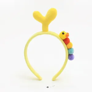 Detail of plush yellow headband featuring a cute colorful caterpillar and sprout accessory