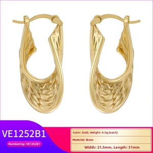 Detail of gold twisted wave hoop earrings in brass with 21.5mm width and 31mm length