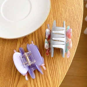 Camellia acetate hair clips in purple and speckled grey on a rustic wooden table
