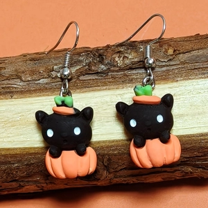 Detail of Halloween drop earrings featuring resin black cat and orange pumpkin on wood