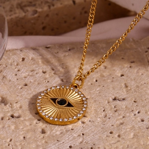 Macro shot of 18K gold plated evil eye coin pendant with sparkling white zirconia stones