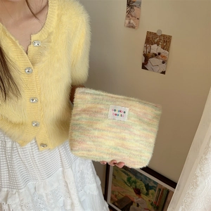 Macro view of plush rainbow makeup bag featuring embroidered label and soft textures