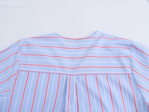 Detail of blue striped cotton shirt featuring a horizontal stripe yoke and pink stitching