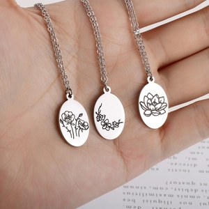 Three oval stainless steel flower pendant necklaces with intricate botanical engravings