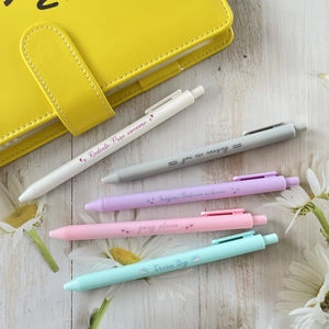Detailed flat lay of 5-piece pastel retractable gel pen set on a wood background