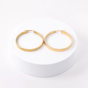 Detailed view of large gold hoop earrings with smooth metallic finish on white stand