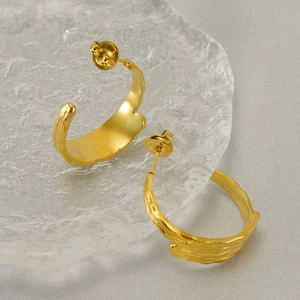 Macro view of gold-plated stainless steel earrings with organic lava texture