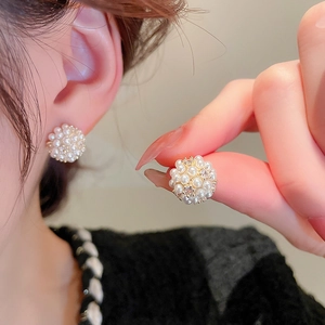 Detailed view of cluster earrings featuring white pearls and zircon on gold plating