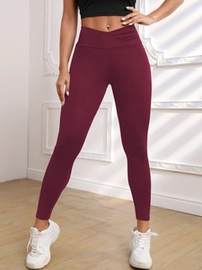 Detail of high waisted yoga leggings in burgundy with stylish cross waist pleat design