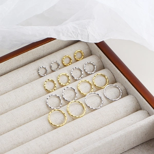 Detailed top view of gold and silver textured hoop earrings in a wooden jewelry box