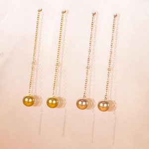 Detailed view of long gold tassel chain earrings with round beads and minimalist ear studs