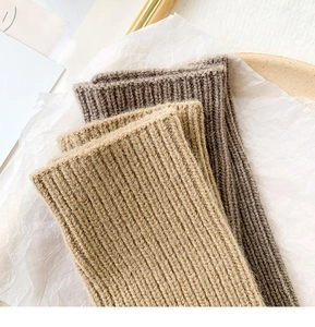 Close-up of thick rib-knitted wrist warmers in coffee and dark grey wool blend