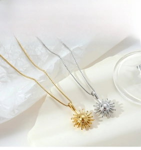 Detail view of gold and silver sunburst pendants on fine stainless steel chain necklaces