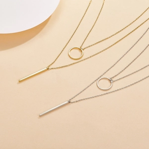 Detail view of double-layered gold and silver necklaces with geometric circle and bar pendants