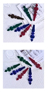 Detailed view of ribbed velvet drop ornaments in dark green, red, and blue colors