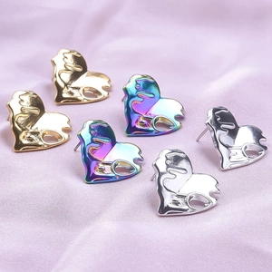 Detailed view of fluid heart stud earrings in gold, silver, and iridescent finishes