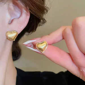Elegant gold heart stud earrings with brushed metal texture and polished edges for women