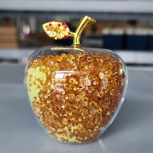 Close-up of decorative crystal apple with golden leaf and orange beaded interior detail