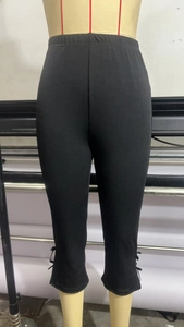 Detail of black cropped flare pants with bow tie decoration on the split hem and elastic waist