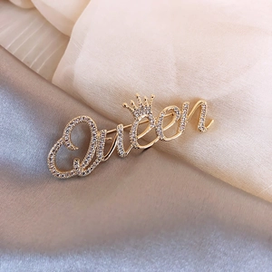 Elegante gouden Queen-letterbroche met kroondetail en glinsterende zirkoon-inleg