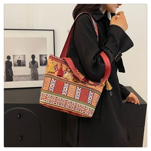 Ethnic crossbody bag with geometric patterns and colorful tassel charms worn by model