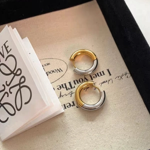 Dettaglio di orecchini a cerchio bicolore in acciaio inossidabile lucido oro 18k e argento