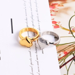 Artistic detail of gold and silver heart-shaped titanium steel rings on white paper