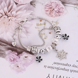 Detailed view of silver snake chain bracelet with floral charms and sparkling beads