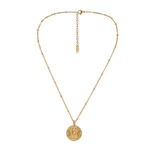 Macro detail of gold stainless steel coin pendant with zodiac relief on bead chain