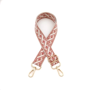 Gros plan d'une bandoulière tissée géométrique rose et blanc avec crochets dorés