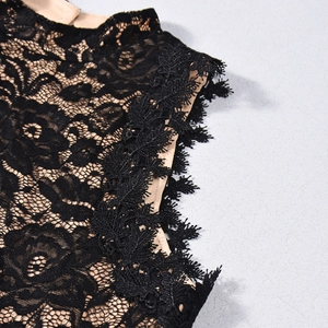 Close-up of black lace fabric showing detailed embroidery and beige lining on jumpsuit