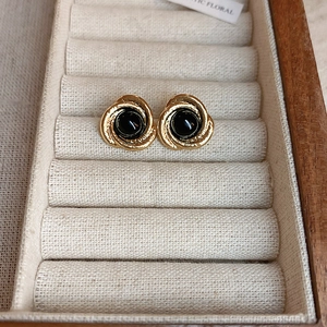 Detailed shot of vintage gold spiral earrings with black stone centers on jewelry tray