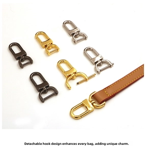 Close-up of swivel metal hooks in gold, silver, and gunmetal on a brown leather strap