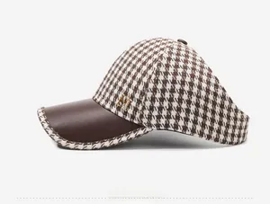 Detail view of houndstooth baseball cap with brown leather brim and gold M logo